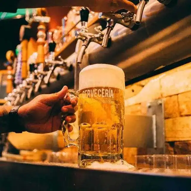 Pinta de cerveza rubia artesanal helada sobre la barra